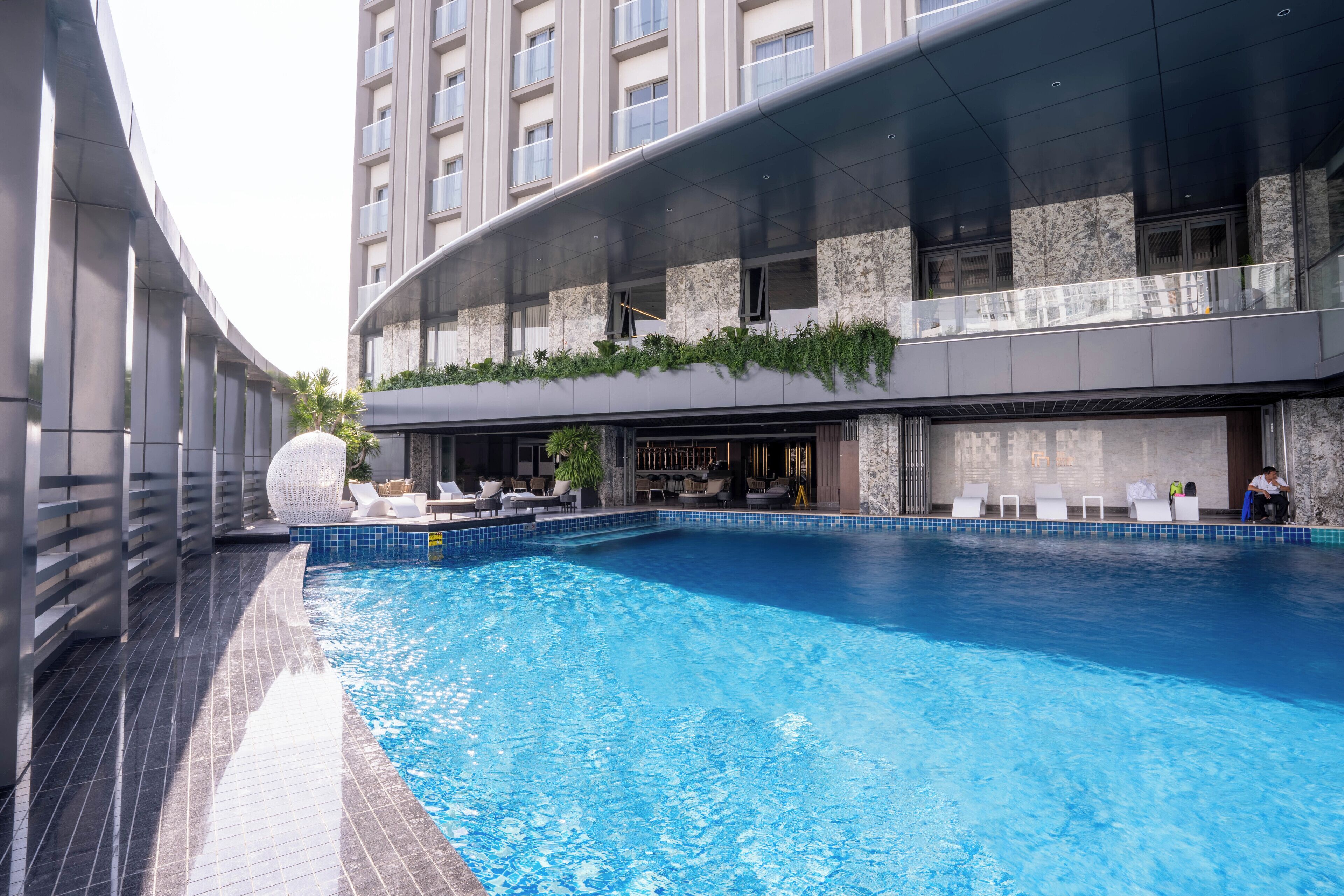 Un hotel moderno con piscina sul tetto, area salotto all'aperto e un bar.