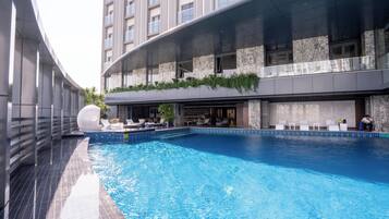Un hotel moderno con piscina sul tetto, area salotto all'aperto e un bar.