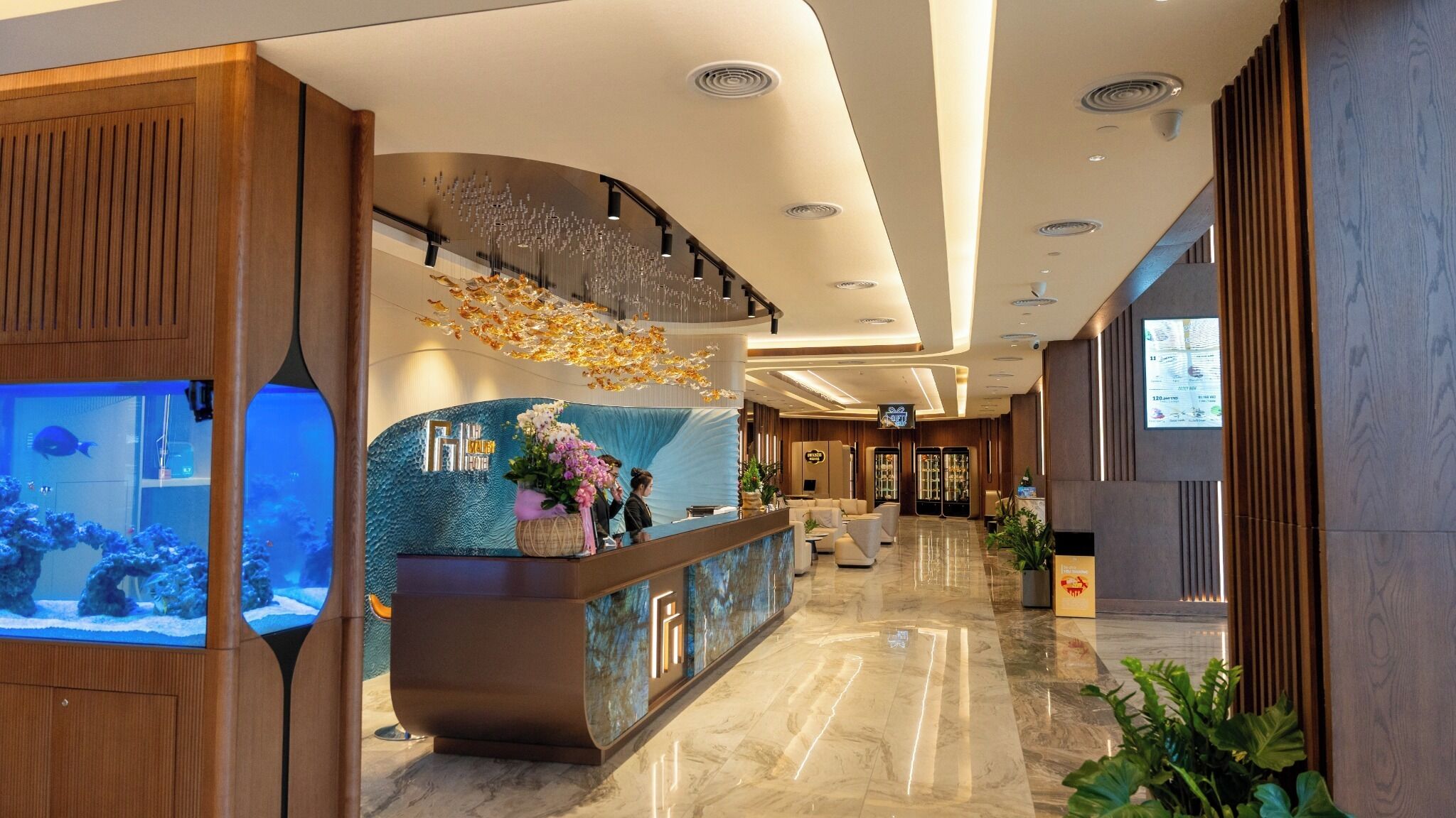 Un vestíbulo de hotel con una recepción, un acuario y una pared decorativa azul.