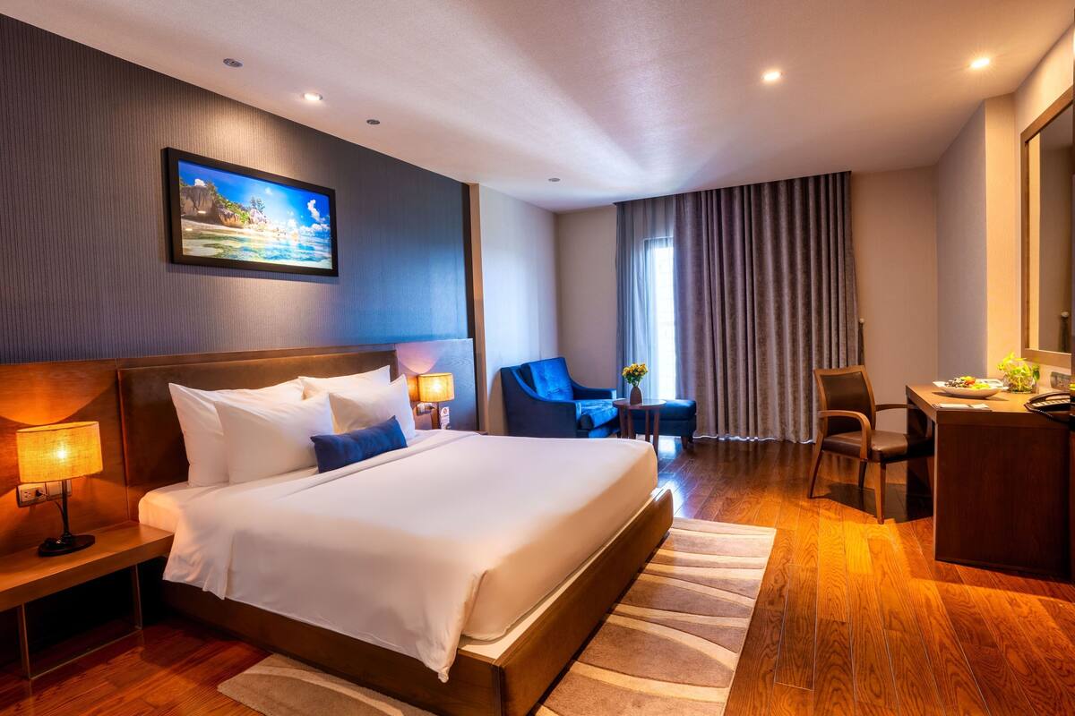 Ein Hotelzimmer mit einem großen Bett, einem Schreibtisch, einem Stuhl und einem kleinen Tisch.