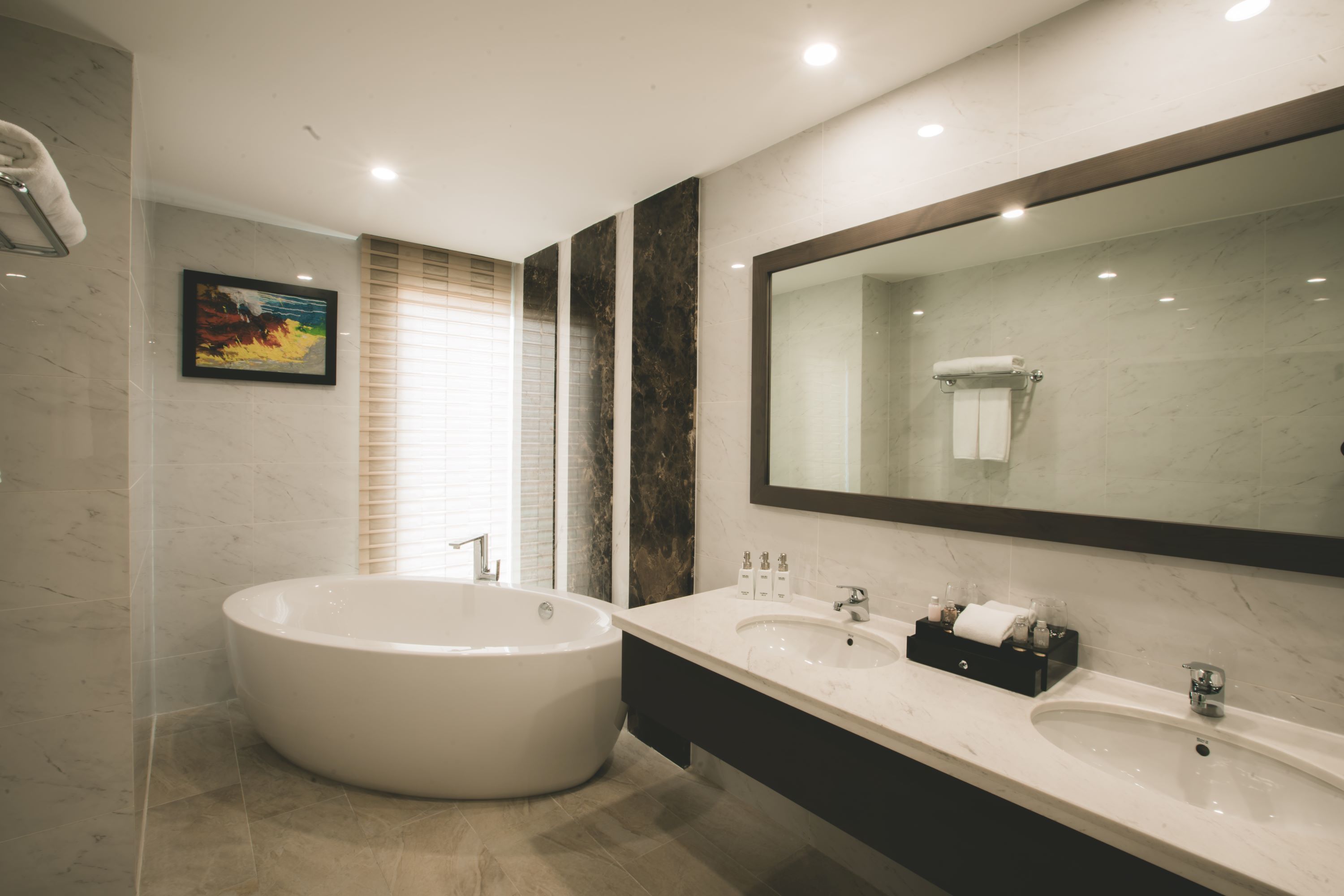 A modern bathroom with a freestanding bathtub, a large mirror, and a vanity with a sink and towel rack.
