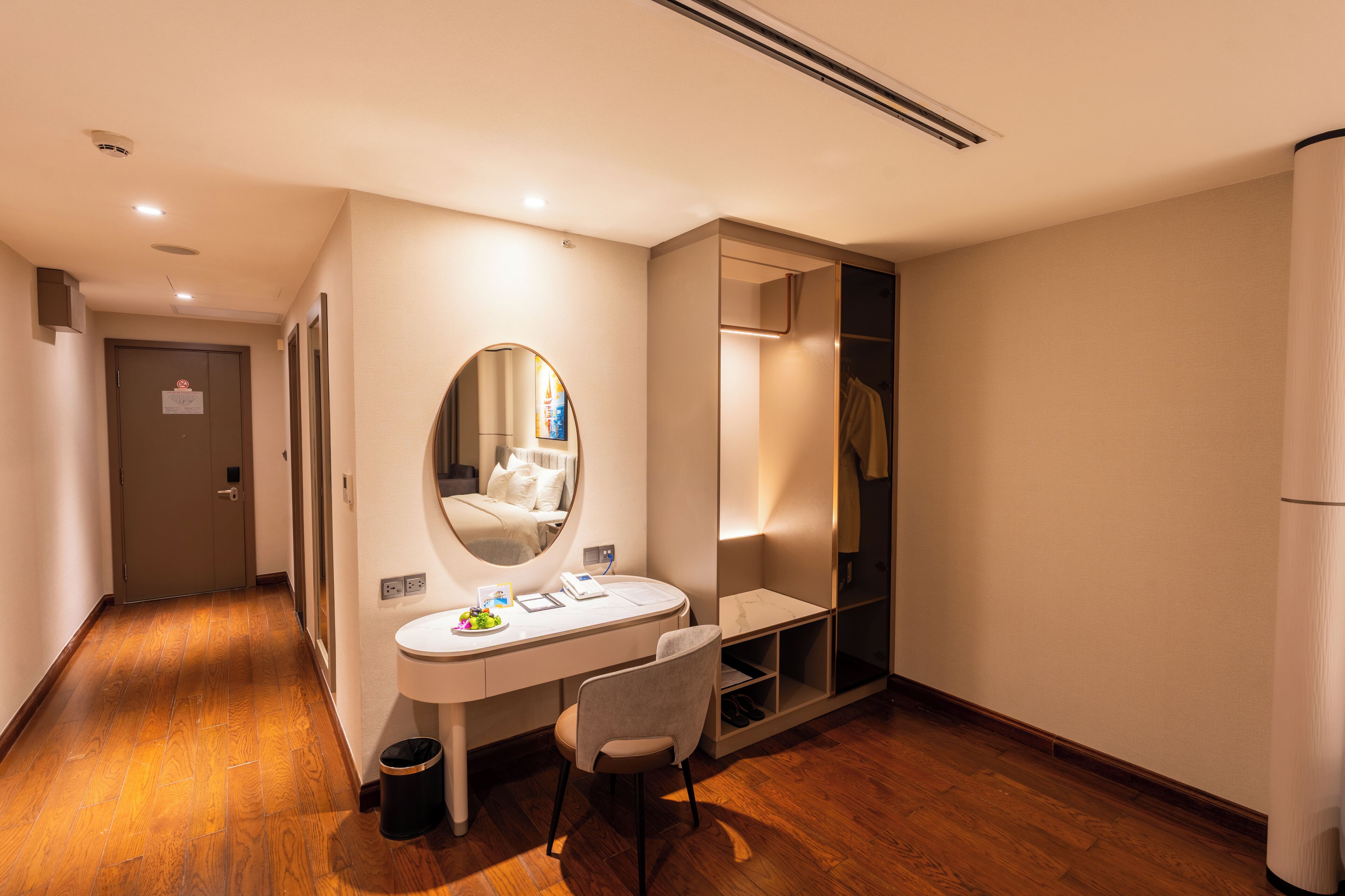 Een hotelkamer met een bureau, stoel, spiegel en een inloopkast.
