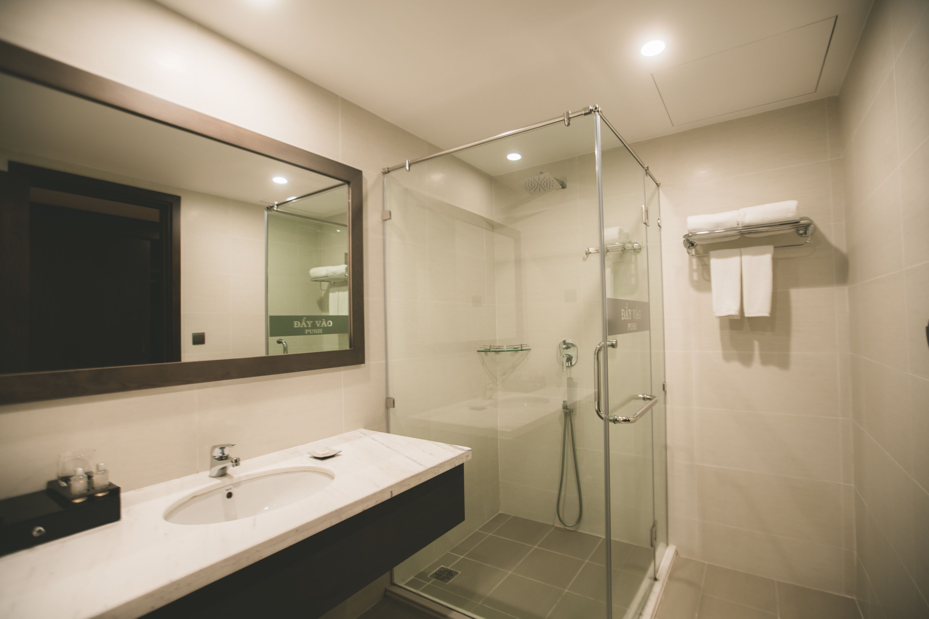 A modern bathroom with a glass-enclosed shower, a sink with a mirror, and a towel rack.