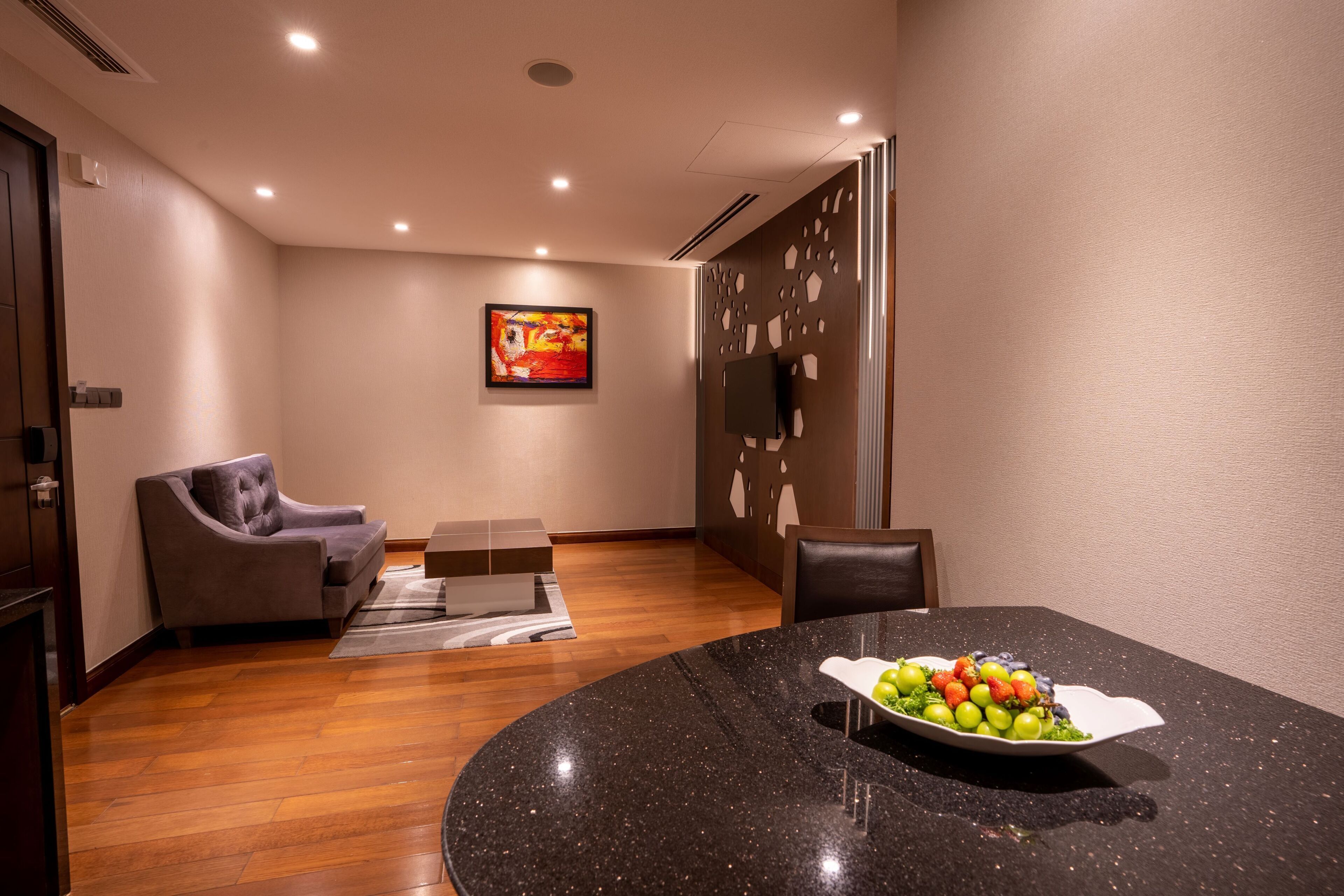 Une pièce moderne avec une table ronde, un canapé gris et un tableau accroché au mur.