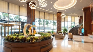 A modern lobby with a central water feature, seating areas, and a staircase. -  The Malibu Hotel (Ho Chi Minh City)