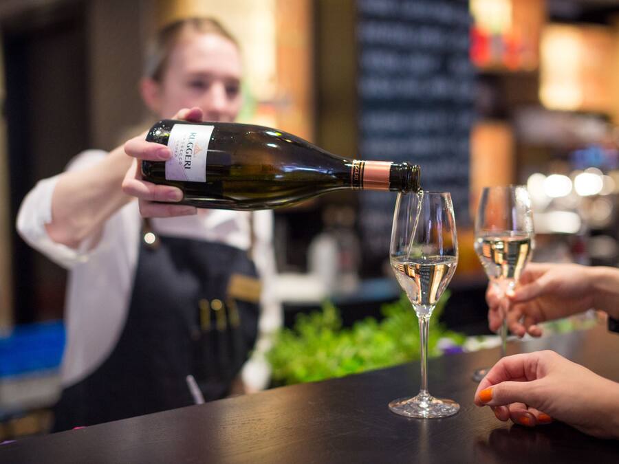 Una persona sirve vino en una copa en un bar.