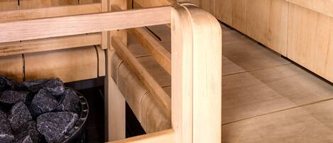 A sauna with wooden benches and a stone heating element.
