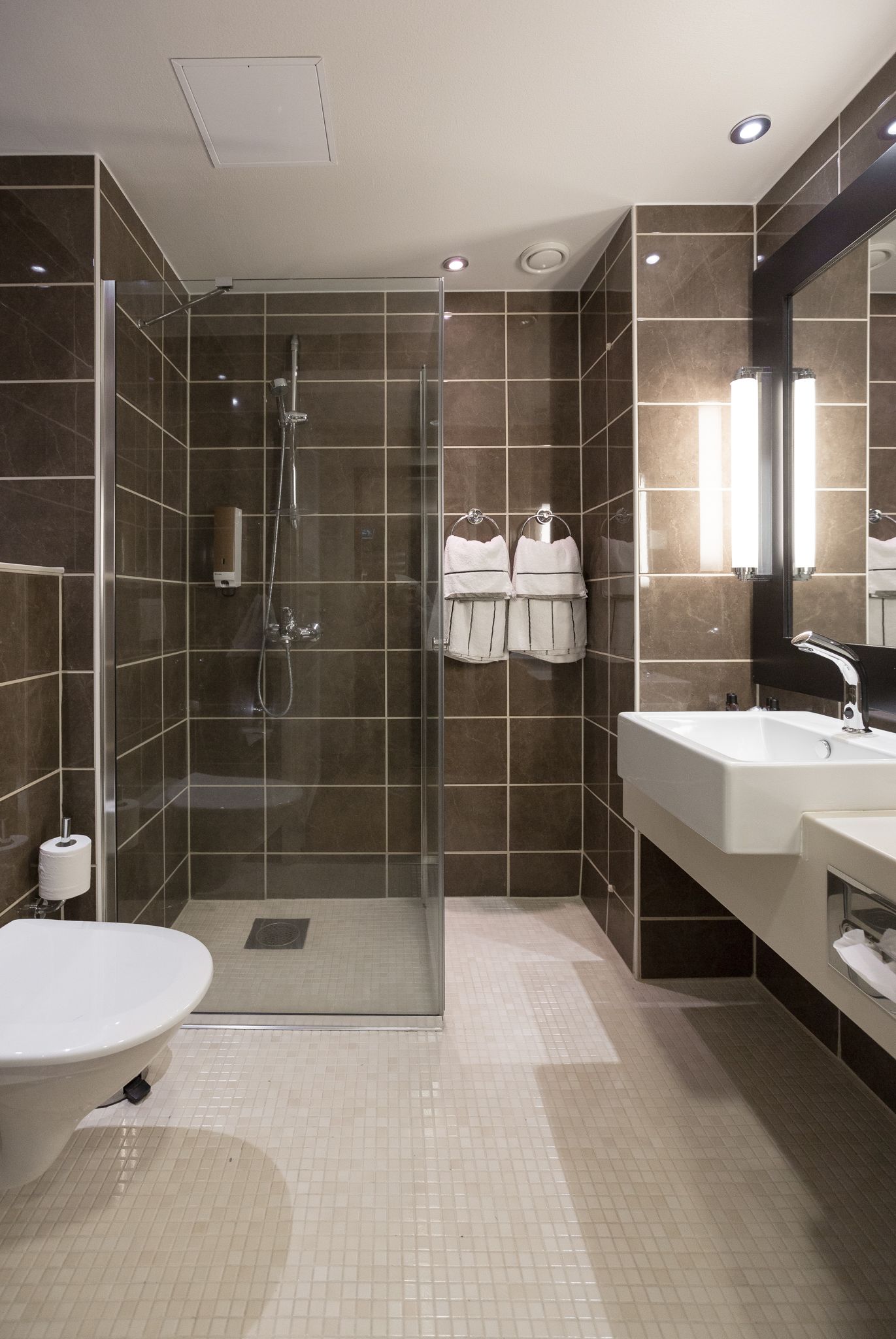 A modern bathroom with a glass-enclosed shower, a white sink, and a large mirror.