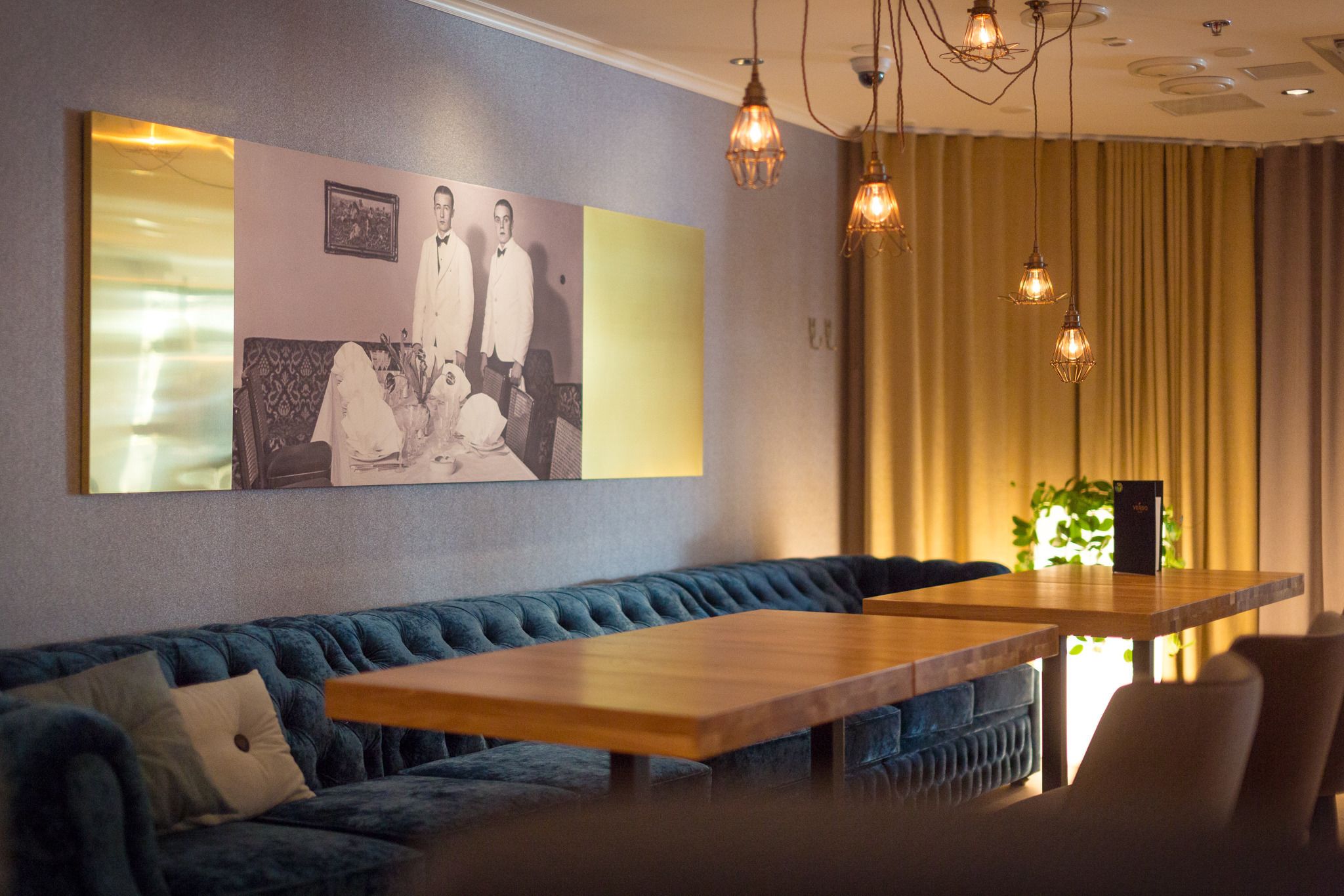 Un espace de détente moderne avec un canapé bleu, une table en bois et des luminaires suspendus.