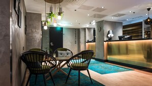 Un espace d’accueil moderne comprenant un comptoir de réception, deux chaises, une table et un tapis bleu.