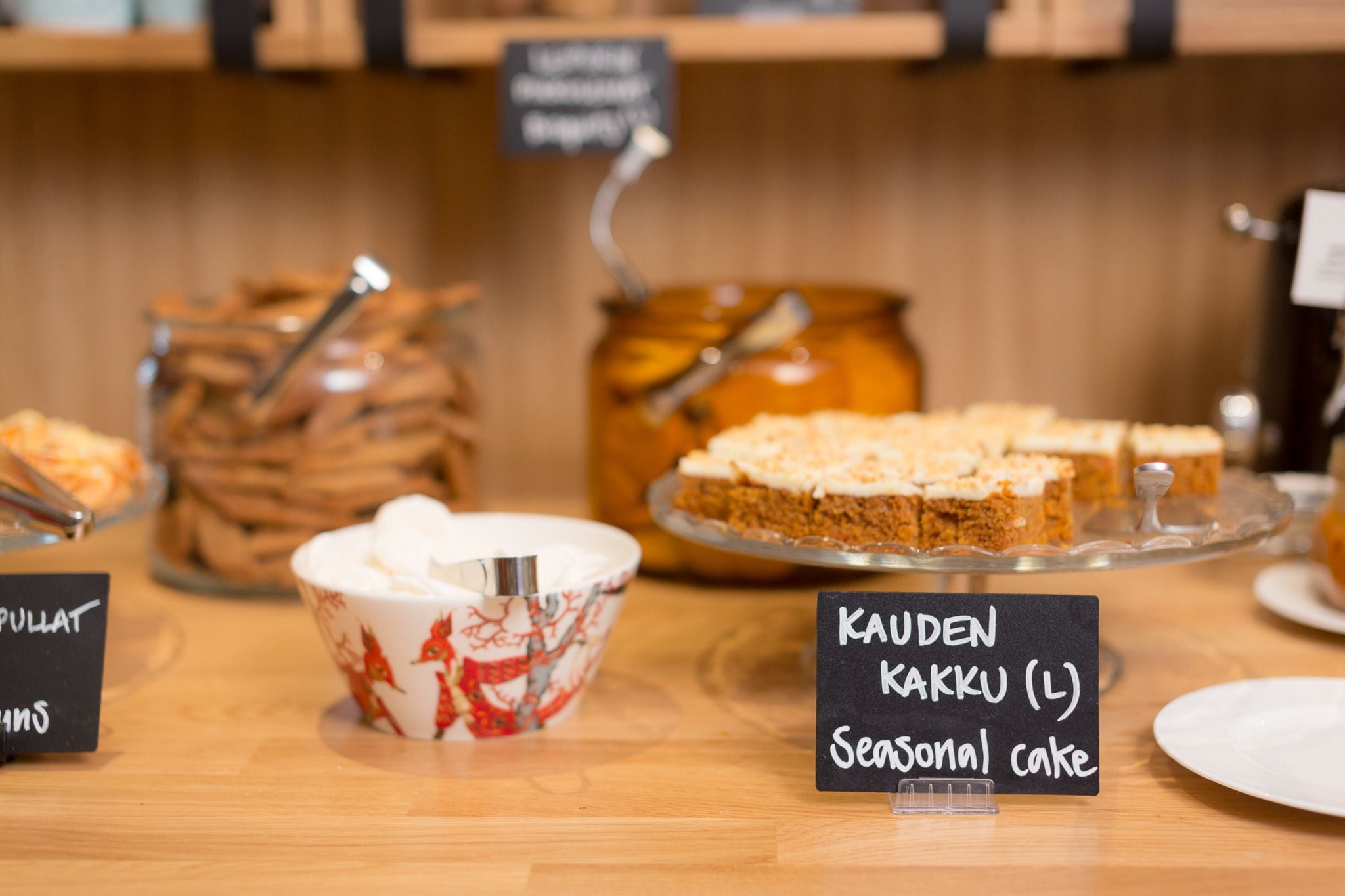 Un espositore di dolci con diversi pasticcini e un cartello che indica una torta di stagione.