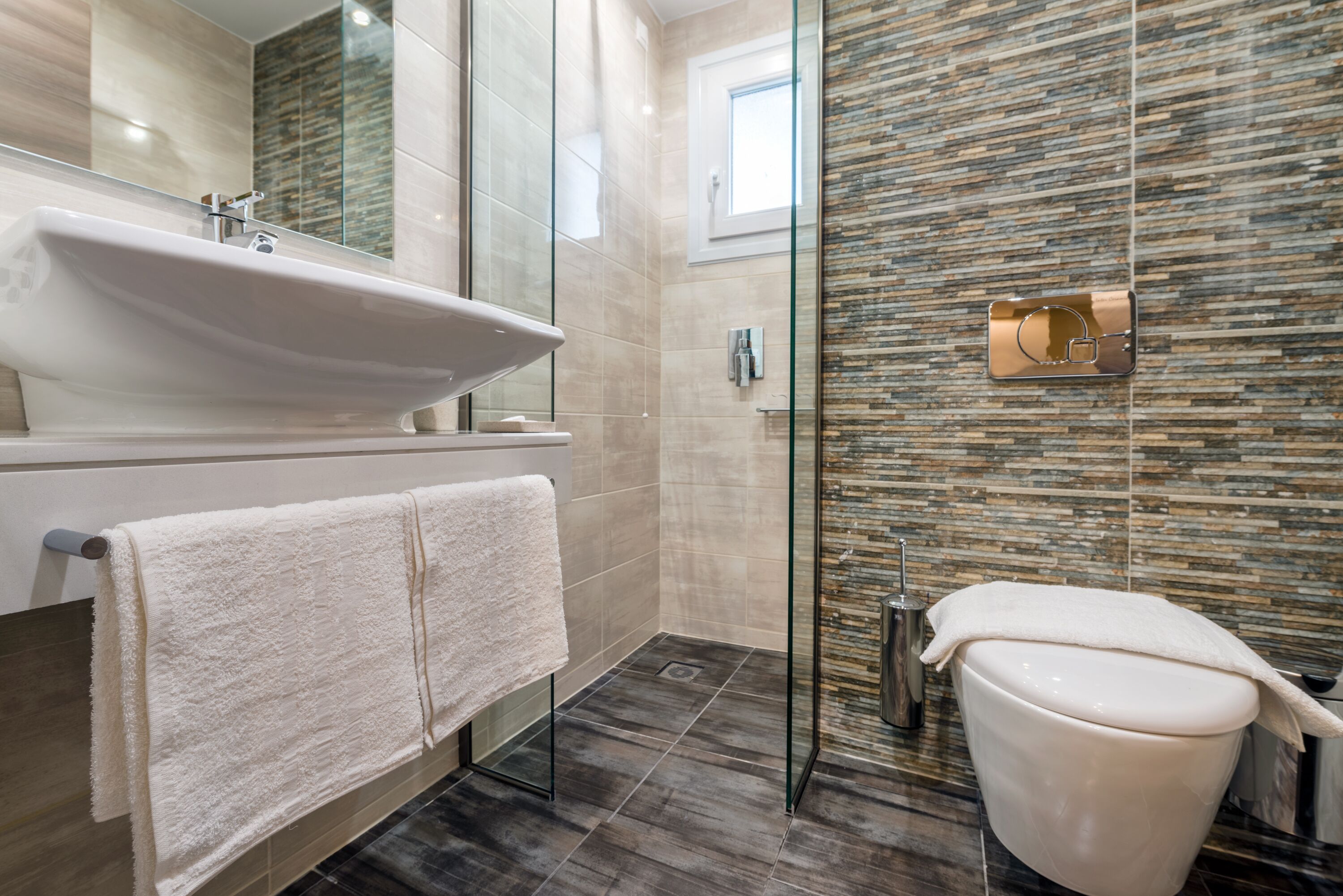 A modern bathroom with a glass shower enclosure, a white sink, and a toilet.