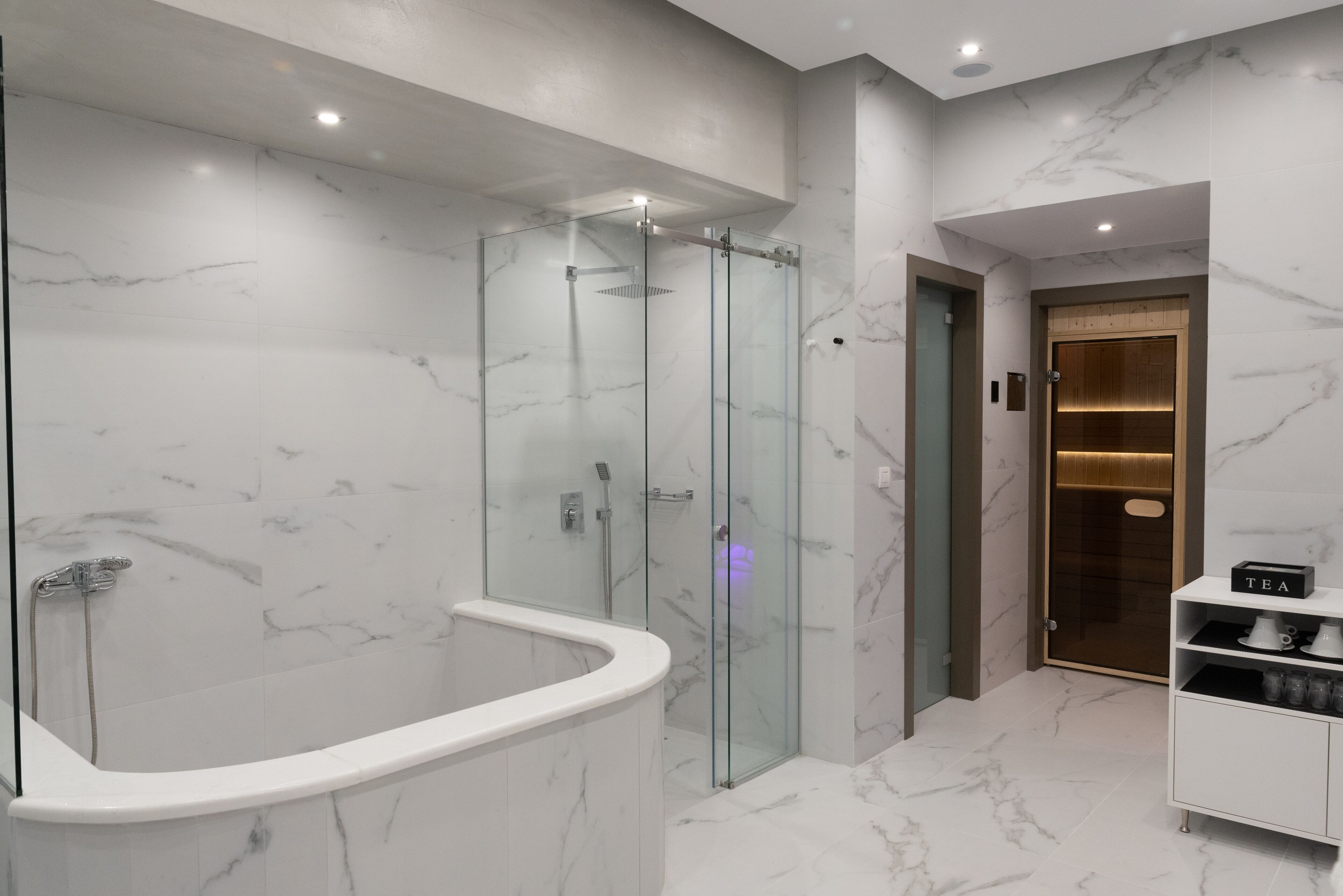 Ein modernes Badezimmer mit einer Glaskabine zur Dusche, einer freistehenden Badewanne und einer integrierten Toilette.