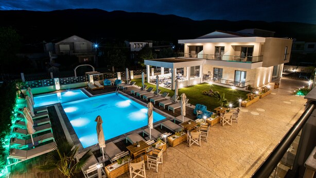 Un hôtel moderne doté d’une piscine, d’un espace extérieur aménagé et d’une terrasse bien éclairée.