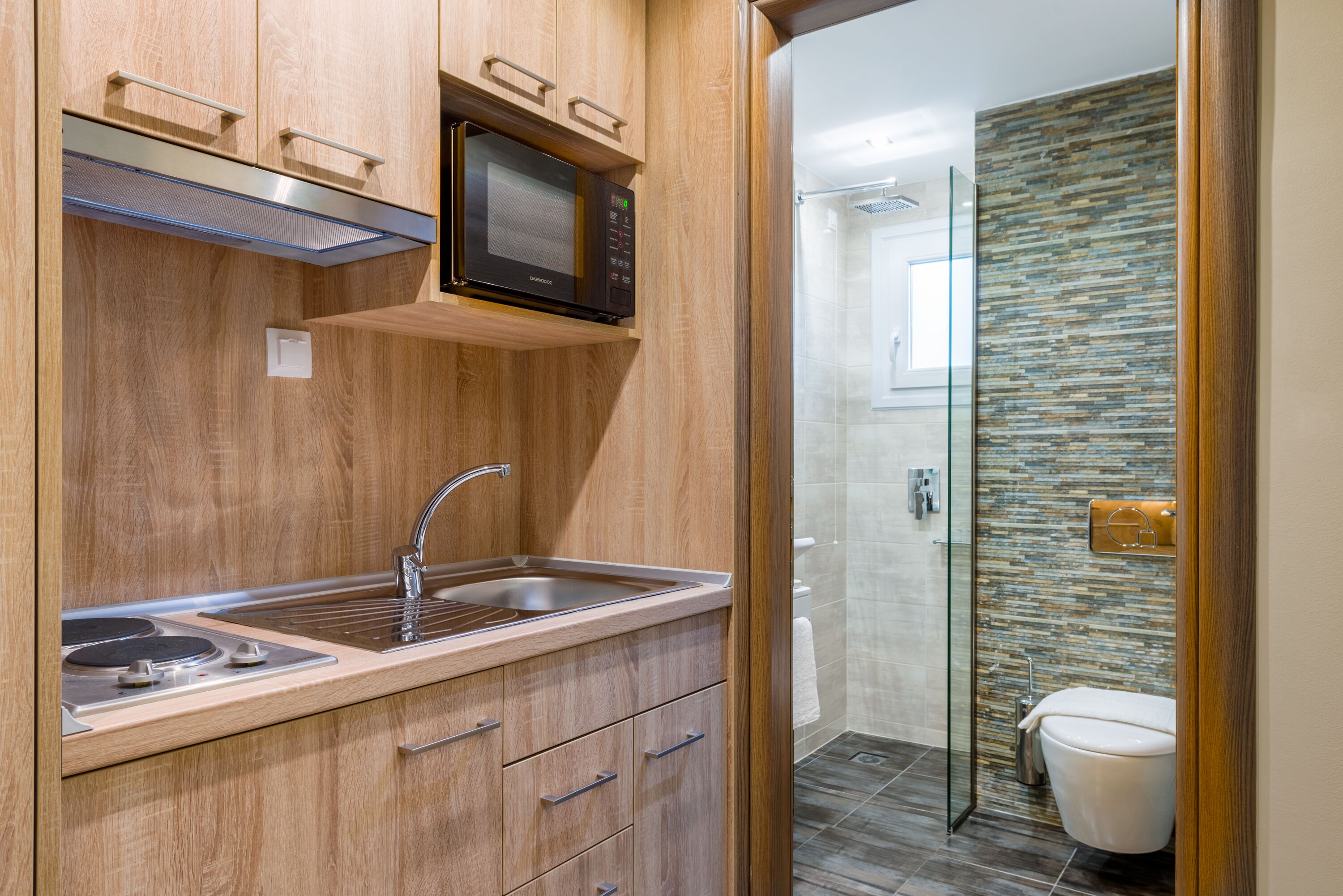 A modern kitchen with a built-in microwave, stainless steel sink, and wooden cabinetry.
