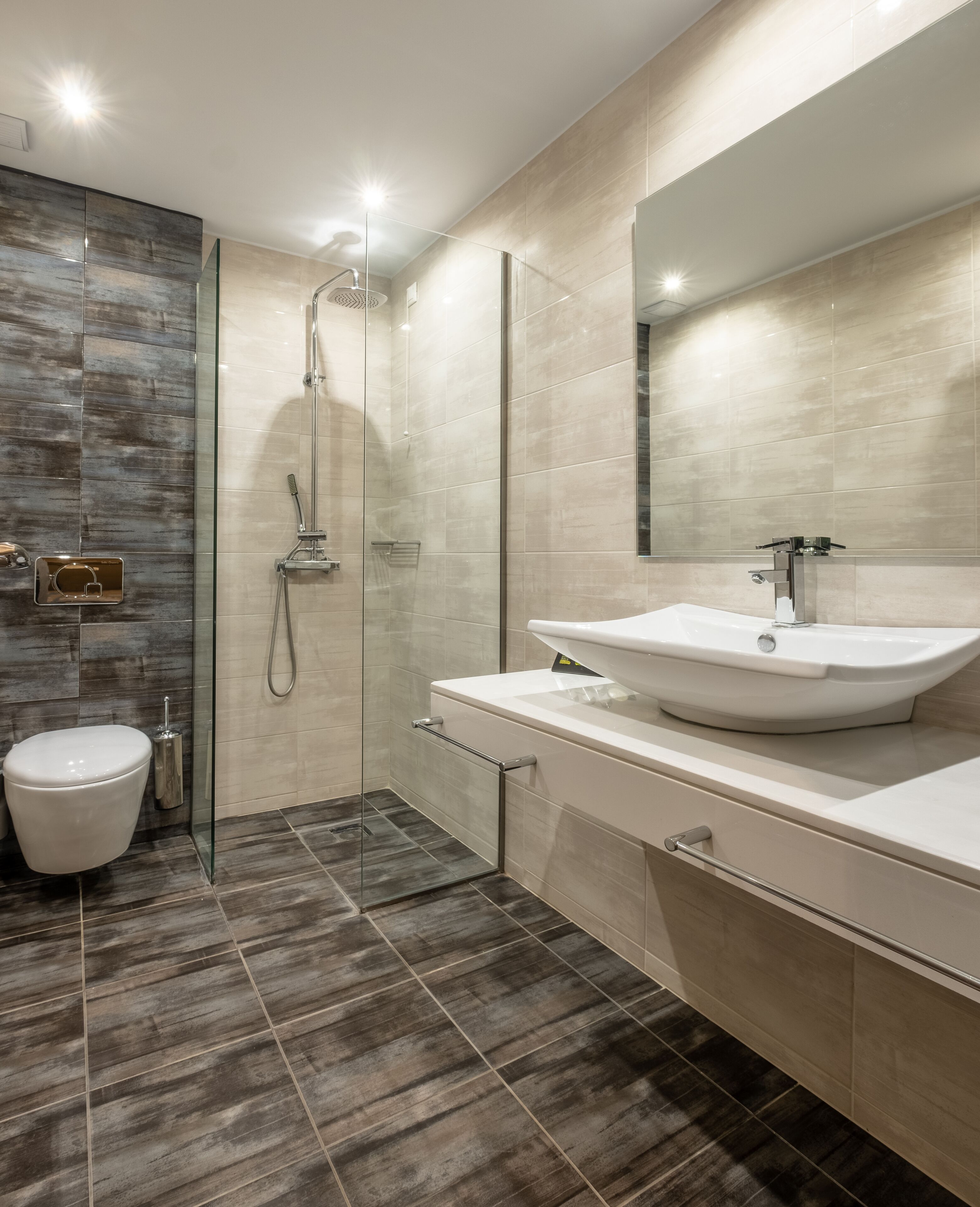 A modern bathroom with a glass-enclosed shower, a white sink, and a toilet.