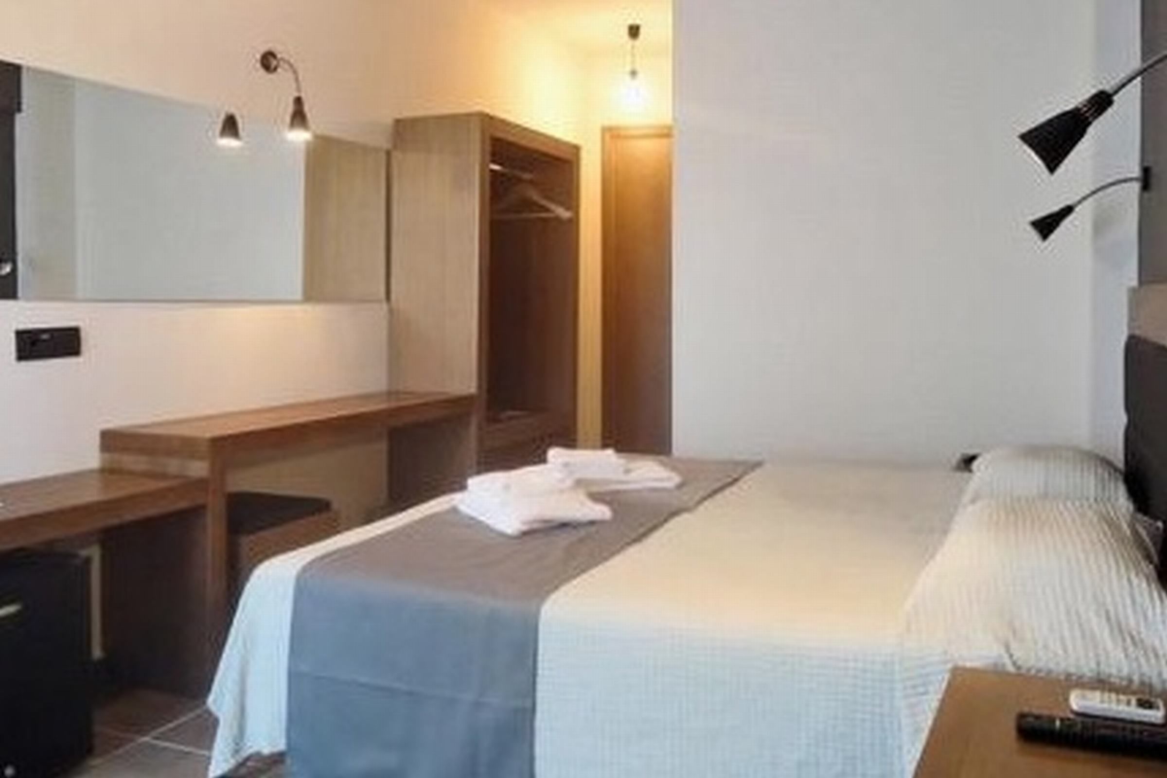 A bedroom with a bed, bedside table, lamp, and a wardrobe.