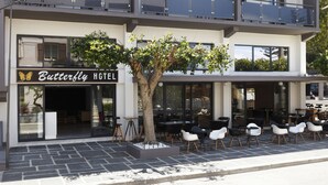Egy „Butterfly Hotel” nevű szálloda, ahol van kültéri ülőhely és egy nagy fa áll az épület előtt.