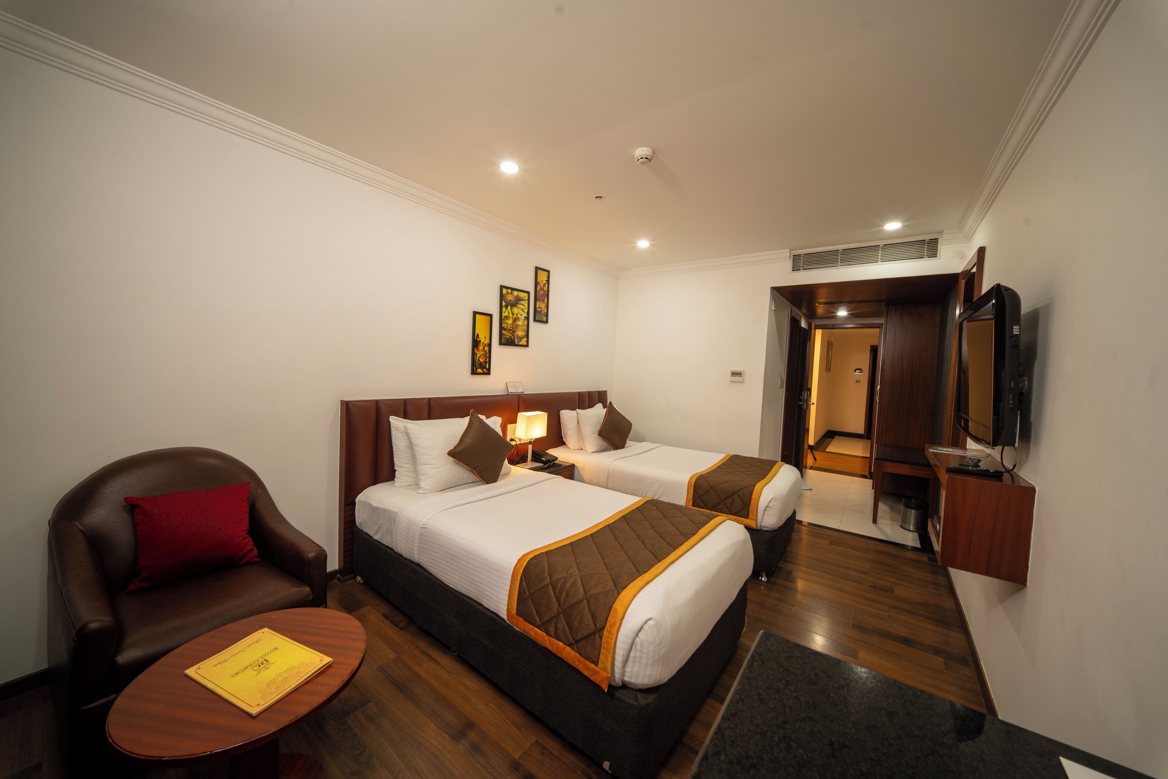 A hotel room with two beds, a sofa, a TV, and a small table.