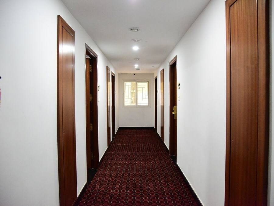 A hallway with wooden doors, a red carpet, and a fire extinguisher on the wall.