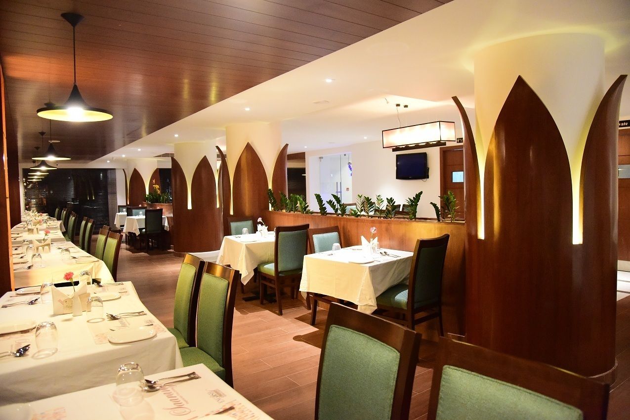 Un restaurant avec de longues tables, des chaises vertes et des éléments décoratifs en bois.