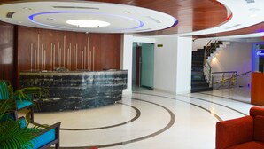 Un vestíbulo moderno con un mostrador de recepción, una escalera y un diseño de techo curvo.