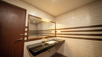 Un baño con puerta de madera, un espejo, un lavabo y azulejos rayados en la pared.