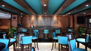 Un área de bar con sillas azules y una pared de ladrillo de fondo.