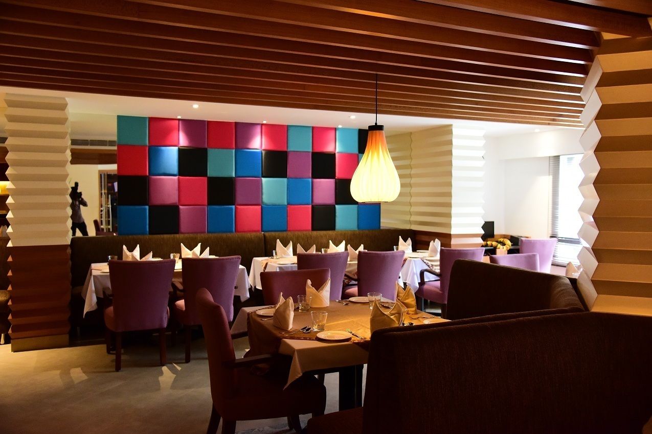 Un restaurant avec des chaises violettes, un mur aux couleurs vives et un luminaire suspendu.