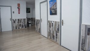 Un couloir avec les portes numérotées 7 et 8, un extincteur et un mur recouvert de carreaux.