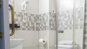 Une salle de bain comprenant des toilettes, un lavabo, une douche et un espace de douche séparé par des parois en verre.