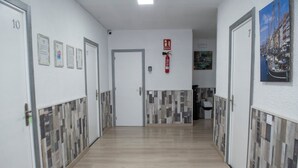 Un couloir avec les portes numérotées 10 et 11, un extincteur et un certificat encadré accroché au mur.