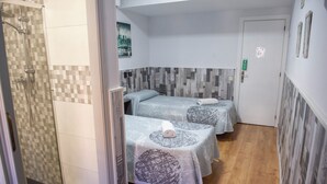 Une chambre d’hôtel avec deux lits, un espace douche et un plancher en bois.