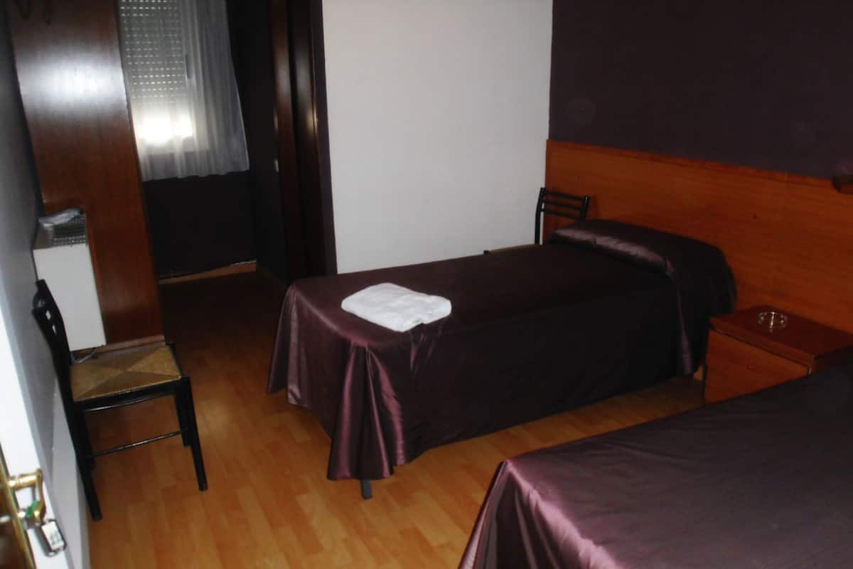 Une chambre avec deux lits simples, un bureau en bois et une chaise.