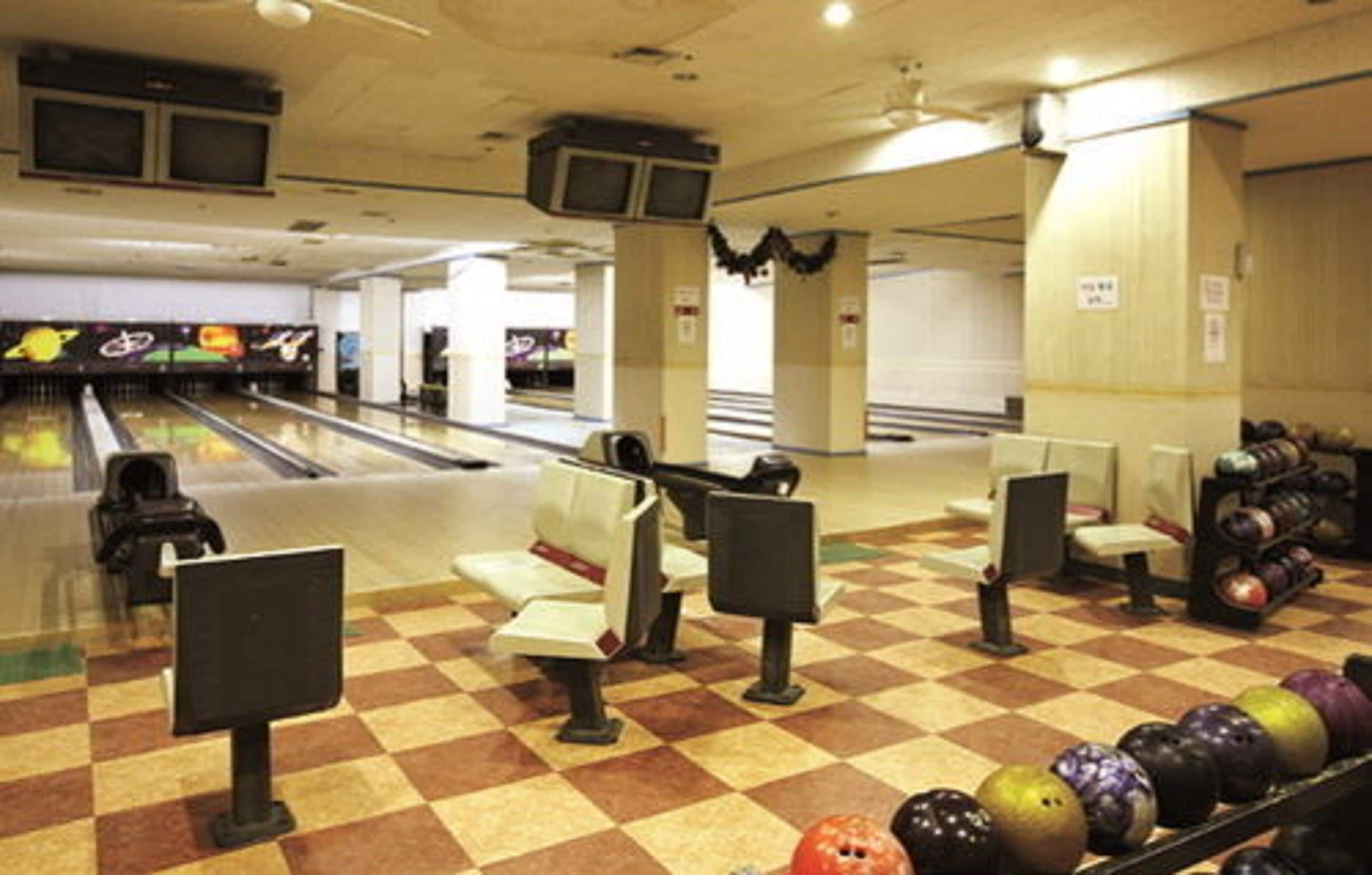 Bolera con pistas, asientos y un estante para pelotas de bolos.