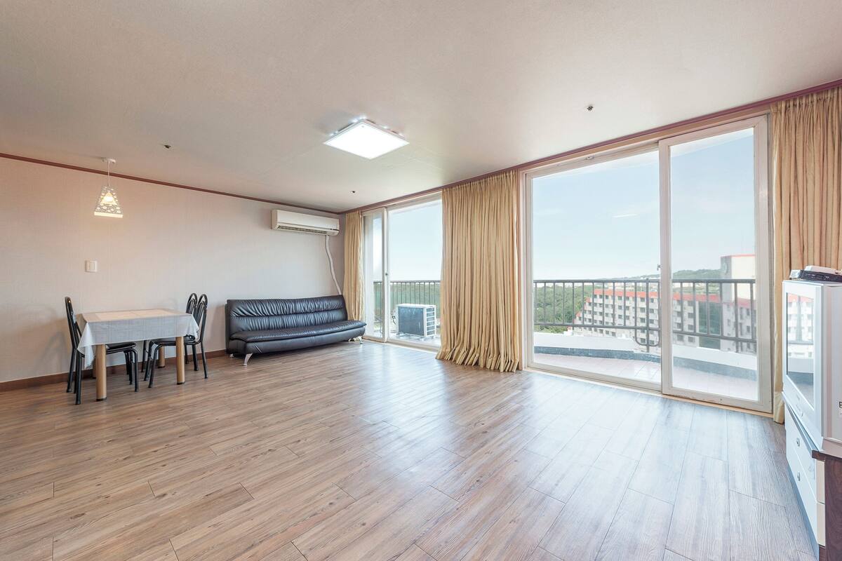 Amplia sala de estar con una mesa de comedor, un sofá y grandes ventanas que ofrecen vistas de la ciudad.
