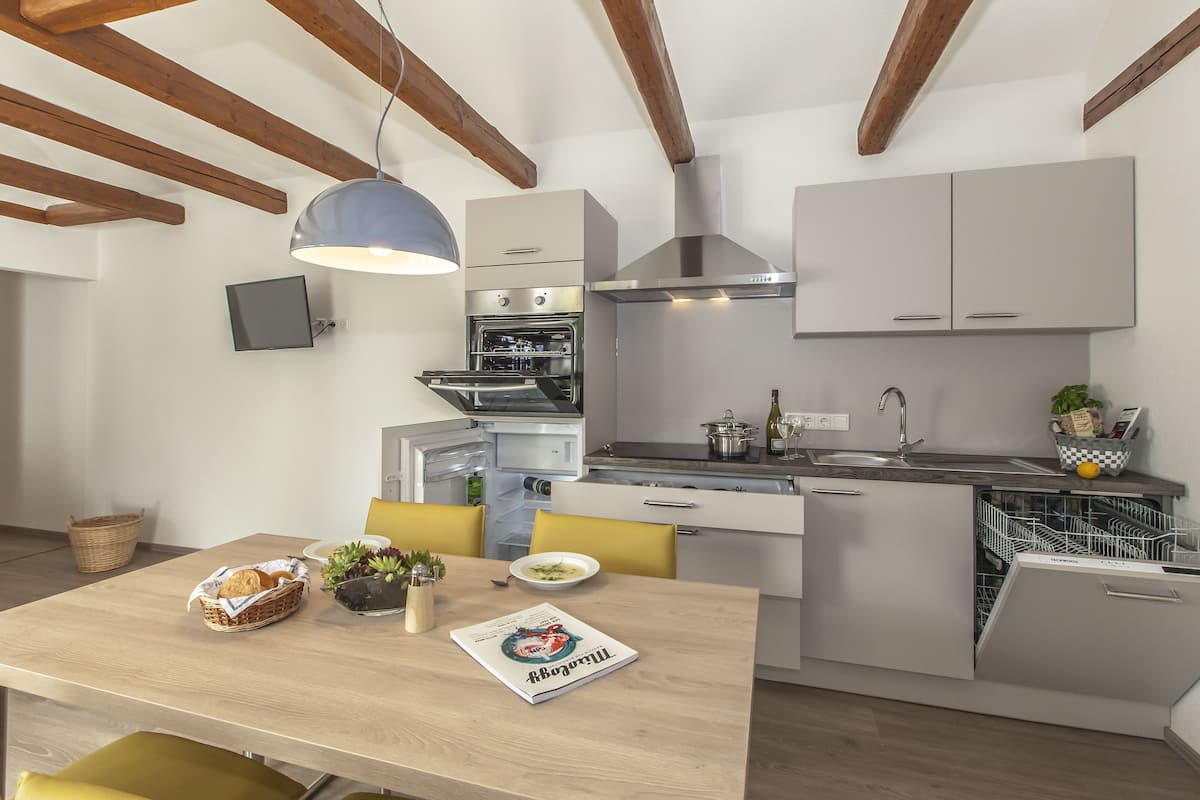 A modern kitchen with a built-in oven, a dishwasher, and a dining area with a table and chairs.