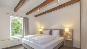 Una camera da letto con un letto grande, travi in legno, una finestra con tende e due lampade da comodino.