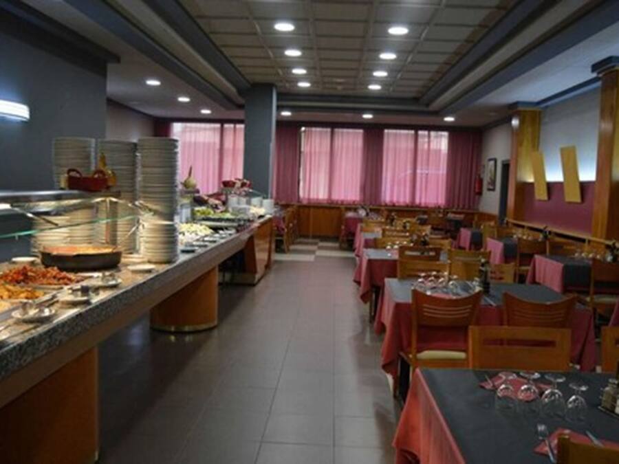 Una mesa de buffet con diferentes opciones de comida y una zona de estar con mesas y sillas.