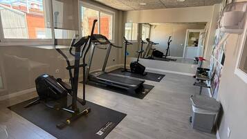 Un gimnasio con cintas de correr, máquinas elípticas y un banco de pesas.