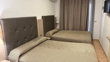 Habitación de hotel con dos camas, televisión, aire acondicionado y ventana con cortinas.