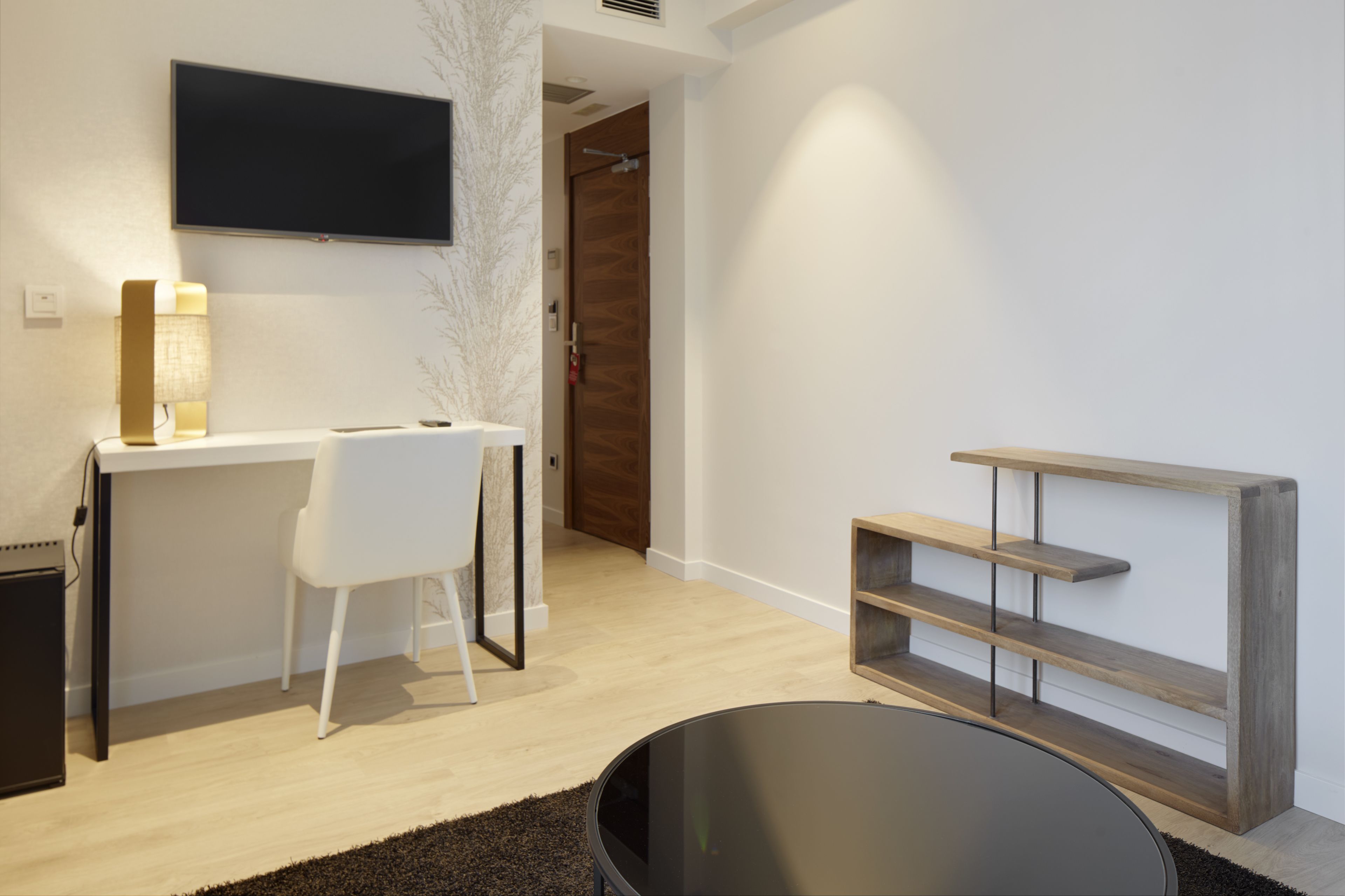 A modern room with a desk, chair, TV, and a wooden shelf unit.
