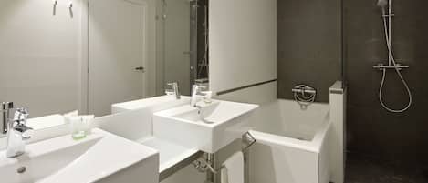 A modern bathroom with two sinks, a bathtub, and a glass-enclosed shower.