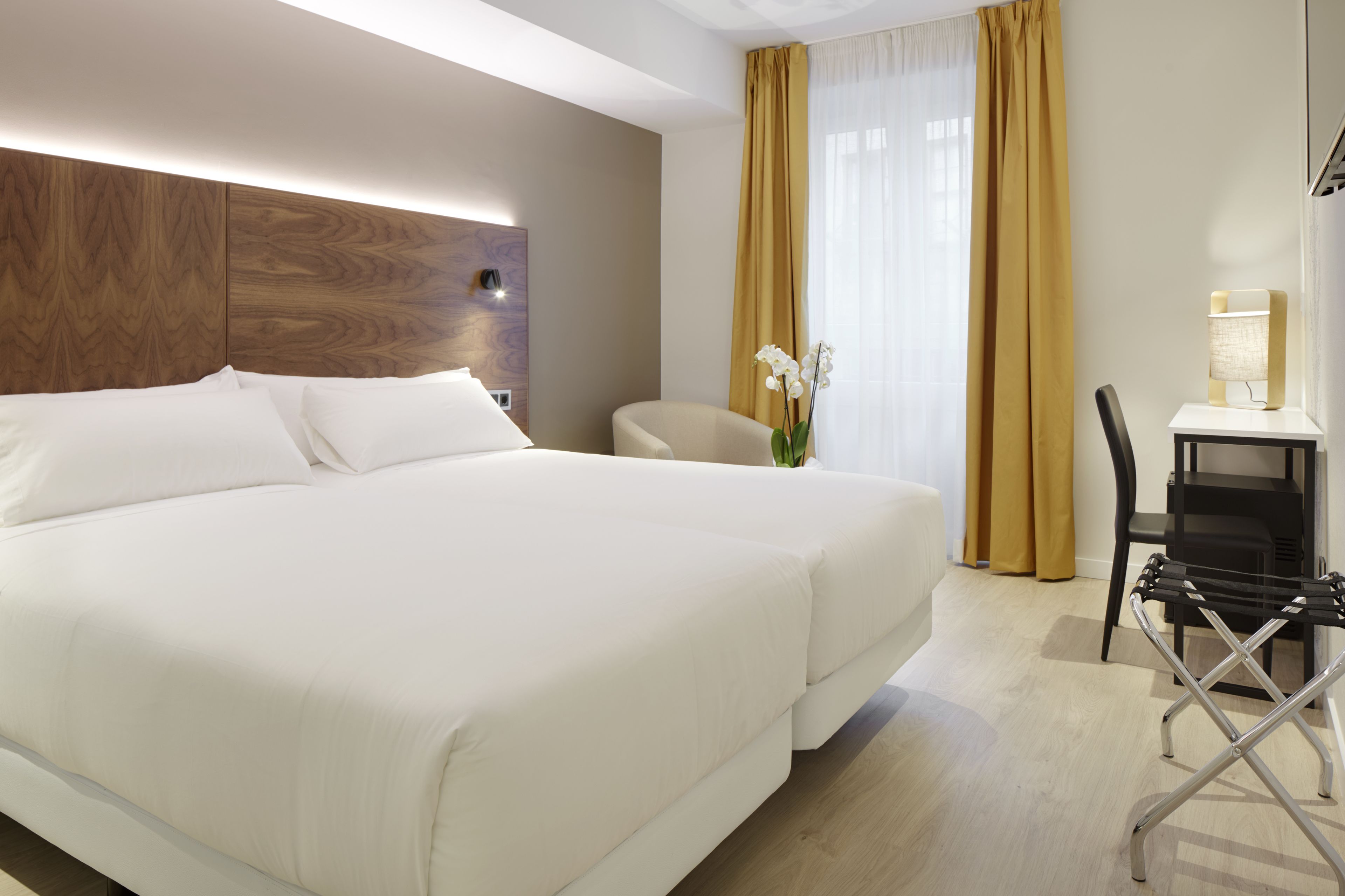 Una habitación de hotel con una cama grande, un escritorio y una silla.