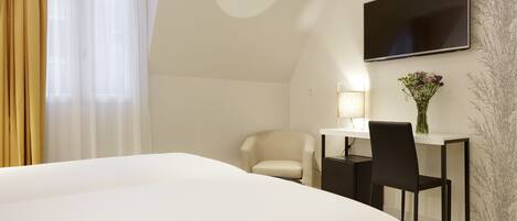 Una habitación de hotel moderna con una cama grande, un escritorio con silla, un televisor de pantalla plana y un jarrón con flores.