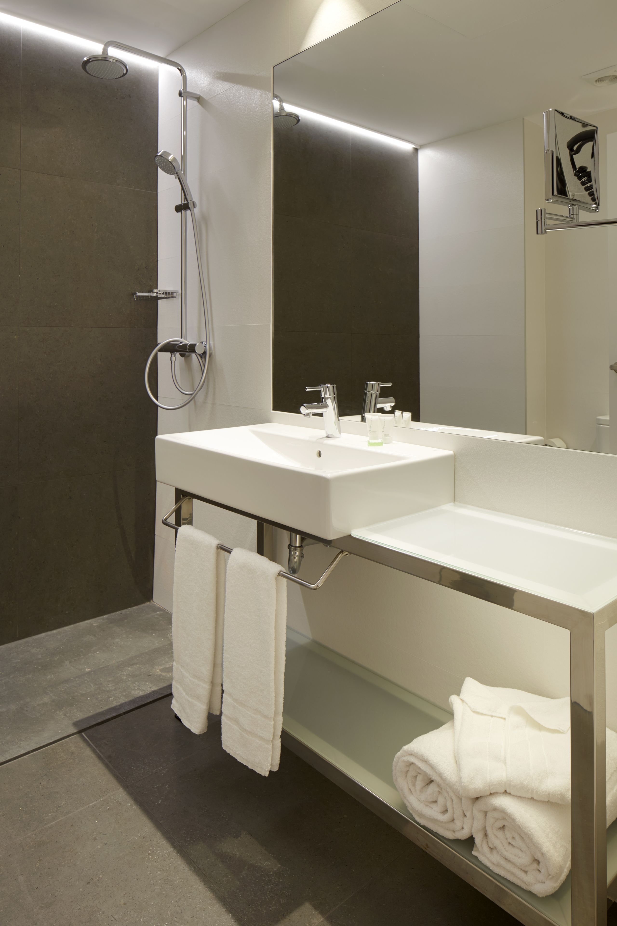 Ein modernes Badezimmer mit einem Doppelwaschtisch, einer Dusche und einem großen Spiegel.