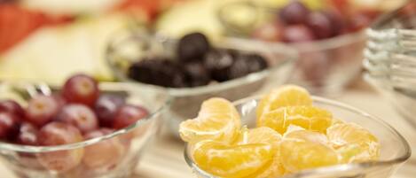 Ein Tisch mit verschiedenen Schalen, gefüllt mit Früchten wie Trauben, Orangen und Brombeeren.