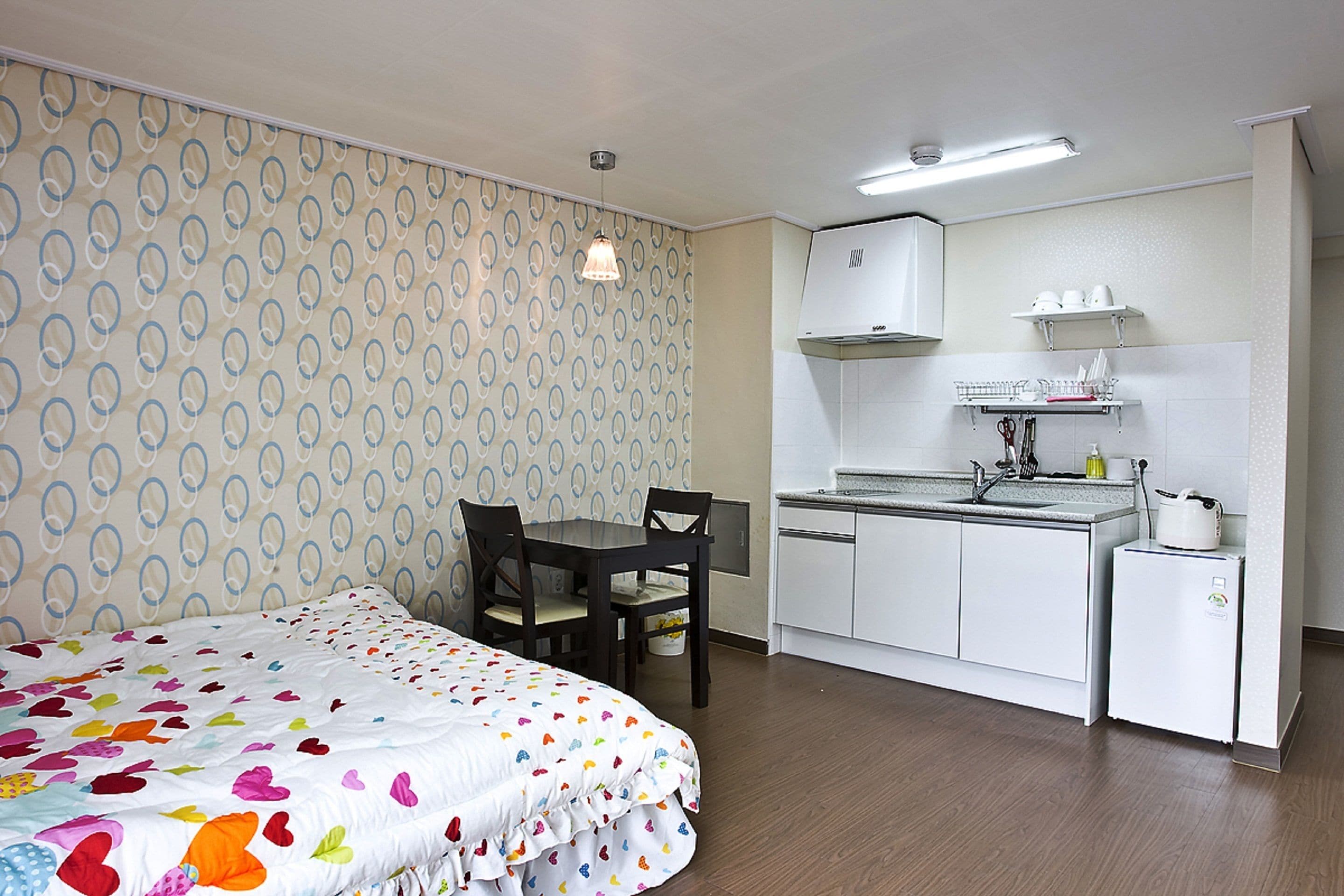 Une petite chambre comprenant un lit, une petite table et un coin cuisine.