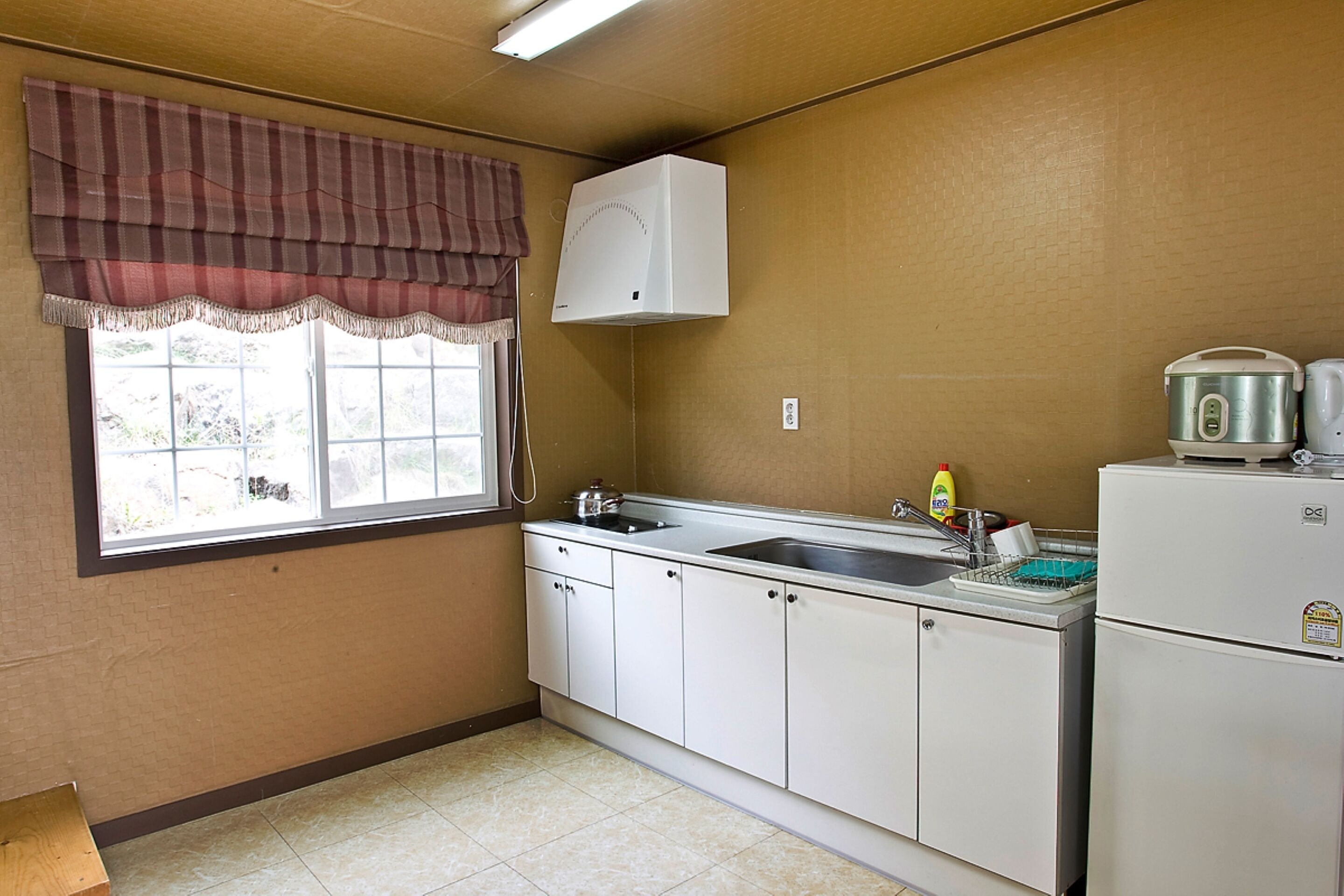 Una cocina pequeña con ventana, un refrigerador blanco y un lavabo.