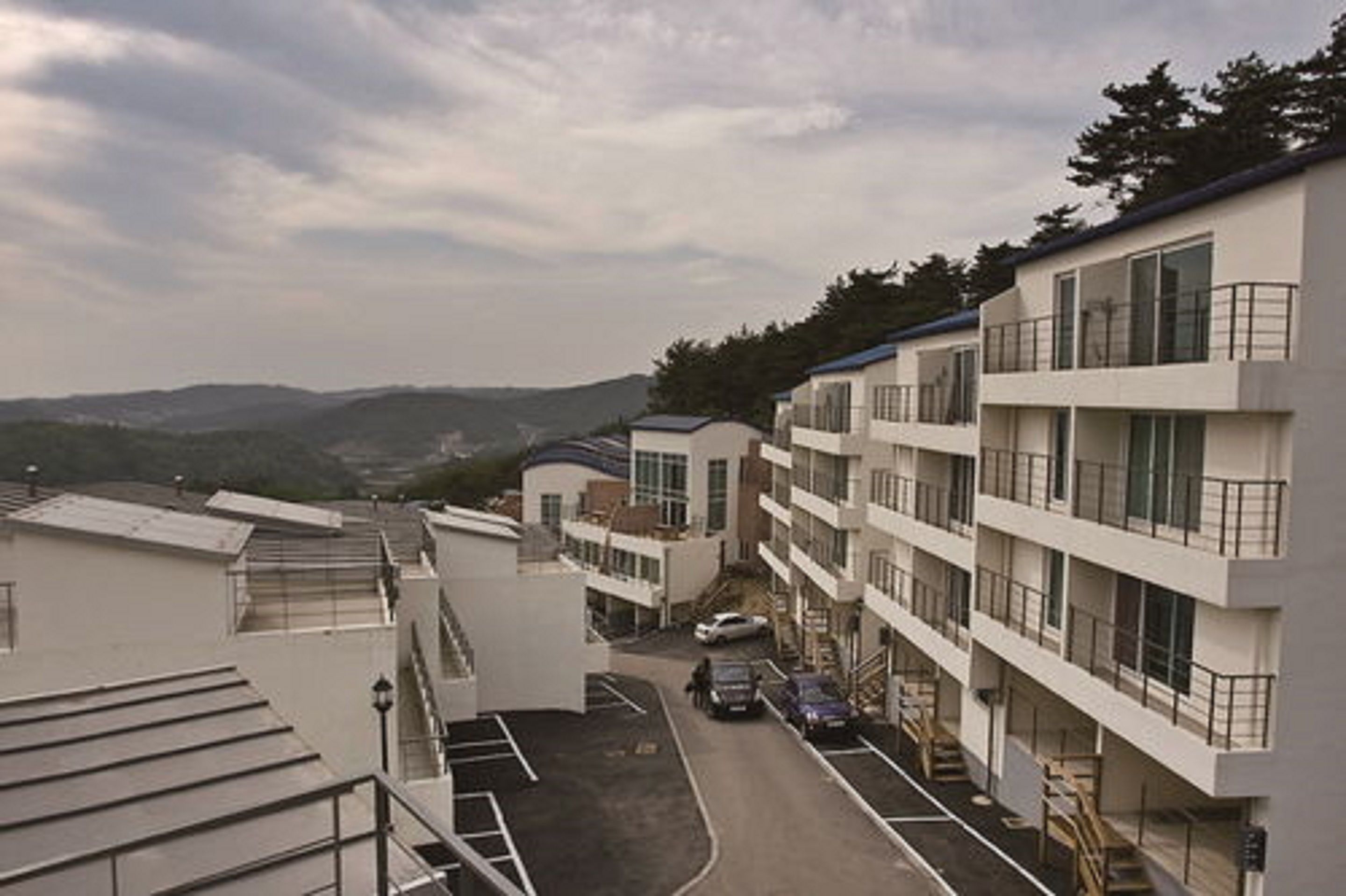 Un hotel de varios pisos con un patio central, arquitectura moderna y vistas a colinas distantes.